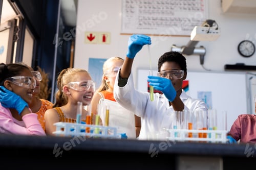 Preview: Diverse female teacher and happy school children doing experiment in chemistry class
