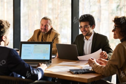 Preview: Group of successful managers looking at male colleague making report