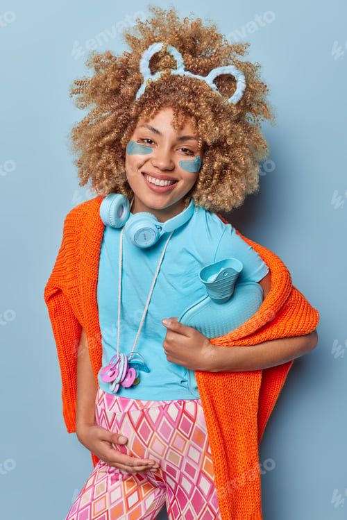 Preview: Vertical shot of happy pregnant woman touches belly keeps rubber hot water bottle under arm applies