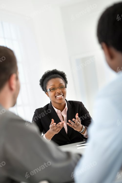 Preview: Three people sitting around a table at a business meeting.