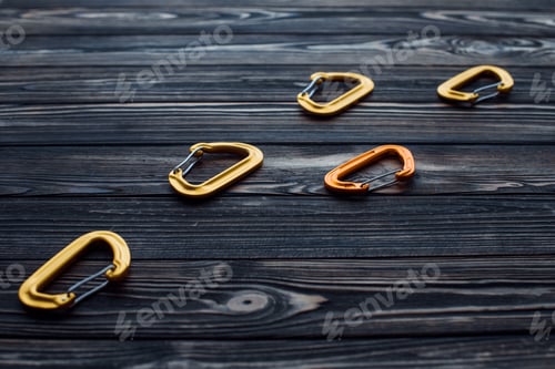 Preview: Isolated photo of climbing equipment. Parts of carabiners lying on the wooden table
