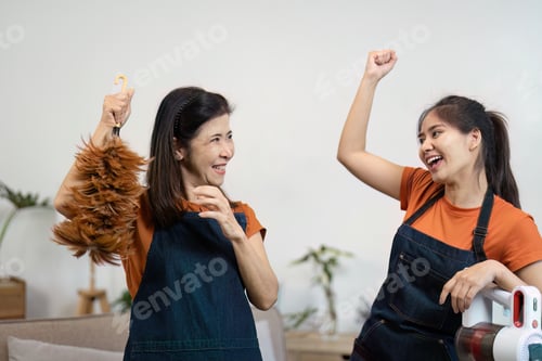 Preview: Joyful Women Engaged in House Cleaning with Feather Duster and Vacuum in Modern Living Room Setting
