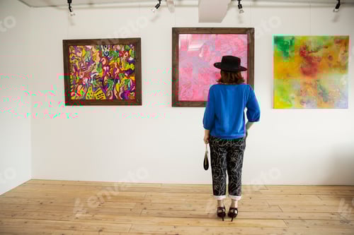 Preview: Japanese woman wearing hat standing in front of abstract painting in an art gallery.
