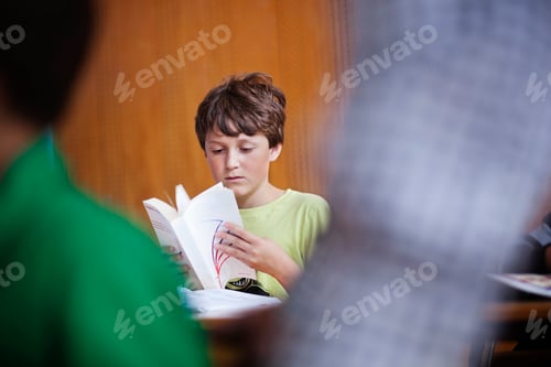 Preview: Boy reading book in classroom at school