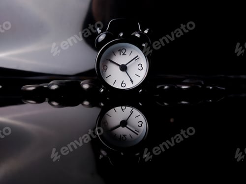 Preview: Black alarm clock and black rock with reflection