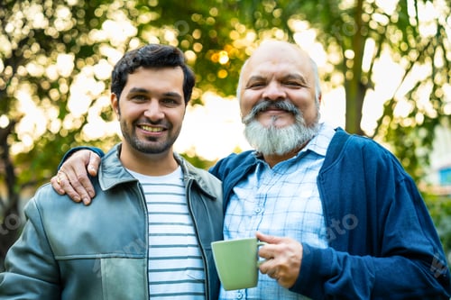 Preview: Indian Asian Old aged father and young adult son walking in a home garden with coffee