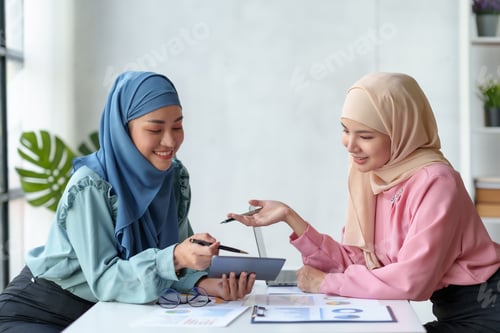 Preview: Team work process Two Muslim business women pointing at a laptop computer and discussing document an