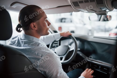 Preview: Careful with driving. Man trying new car in the salon at daytime. Buying new vehicle