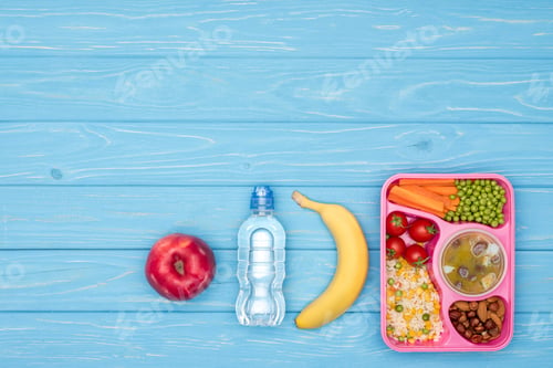Preview: elevated view of tray with kids lunch for school, bottle of water and fruits on blue table