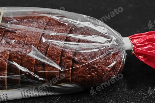 Preview: Sliced black rye bread in plastic bag on dark background