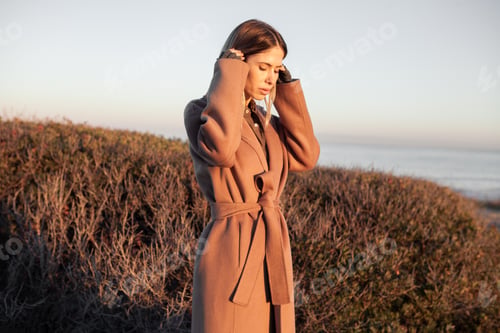 Preview: A beautiful portrait of a woman walking in a coat on the wild coast.