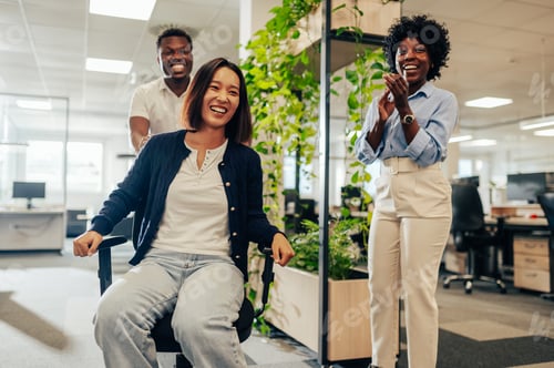 Preview: Asian woman enjoying office chair race at workspace and having fun