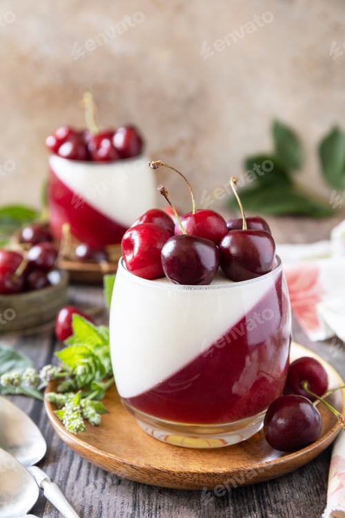 Preview: Panna cotta with sweet cherry jelly on a rustic table.