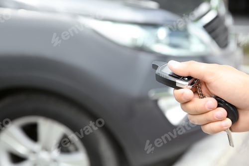 Preview: Young man using car alarm system outdoors