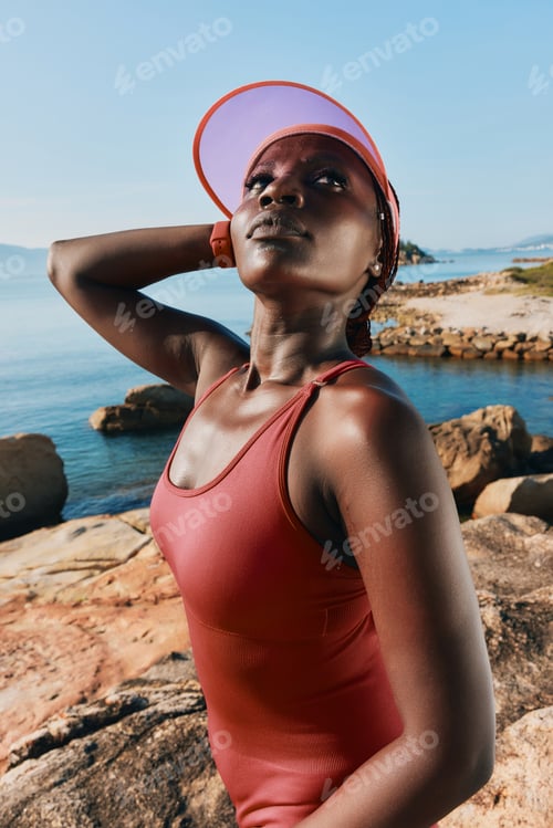 Preview: A confident woman in a swimwear poses near the tranquil sea, wearing a cap and enjoying the summer