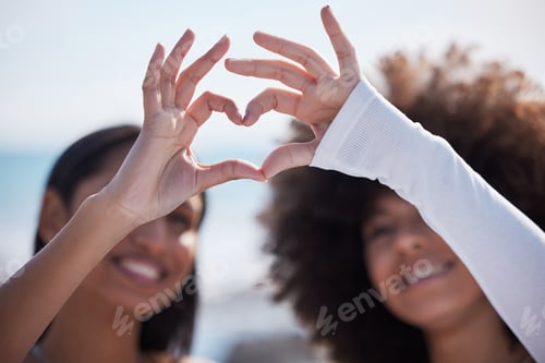 Preview: Closeup shot of two unrecognisable women making a heart shape with their fingers outdoors