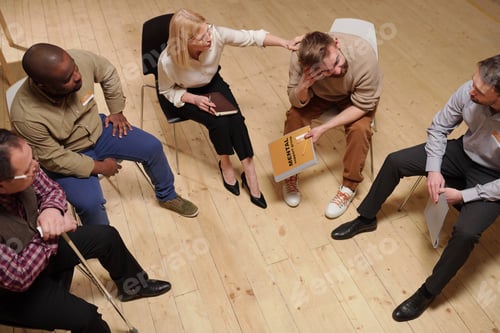 Preview: Blond mature female psychologist touching shoulder of young bearded man while comforting him