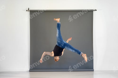 Preview: Fit skilled man performing acrobatic trick in studio