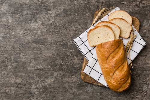 Preview: Freshly baked bread slices on cutting board against white wooden background. top view Sliced bread