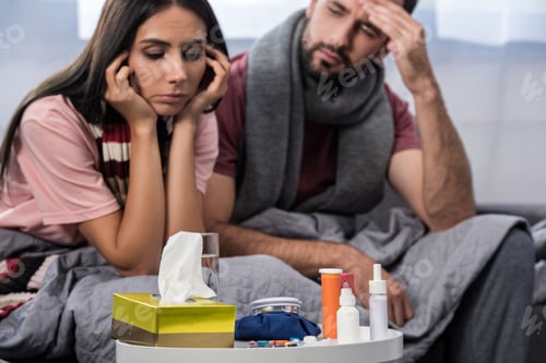 Preview: sick couple with meds on table sitting together on couch