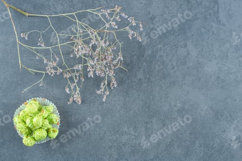 Preview: Small pile of green popcorn candy next to decorative branches on marble background