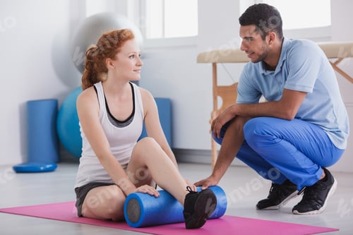 Preview: Woman Using Foam Roller with Trainer Assisting