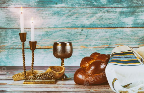 Preview: Shabbat eve table with covered challah bread, candles and cup of wine.