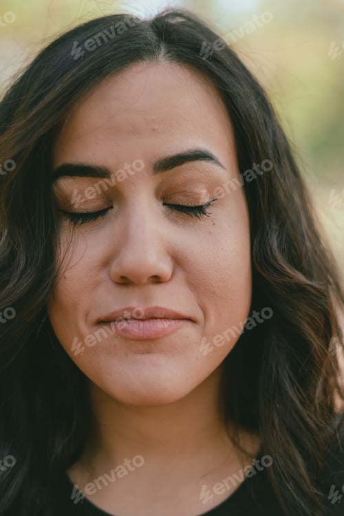 Preview: close-up of hispanic woman with a contemplative expression in natural outdoor lightining