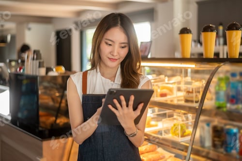 Preview: Woman entrepreneur using tablet checking stock in modern coffee shop