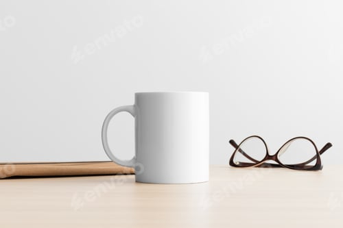 Preview: White mug mockup with workspace accessories on the wooden table.
