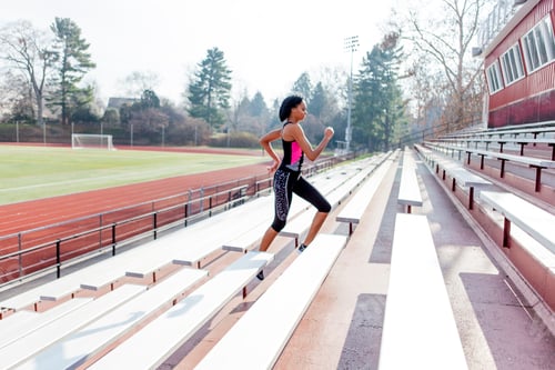 Preview: Young woman running up steps at sports track