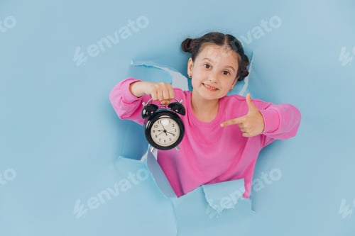 Preview: Little girl looking out of a torn hole in a blue paper and showing a clock, discount time