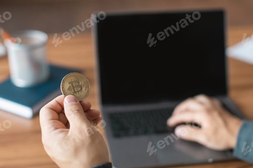 Preview: Middle aged asian man looks at computer with empty screen hold bitcoin, analyzes financial data for