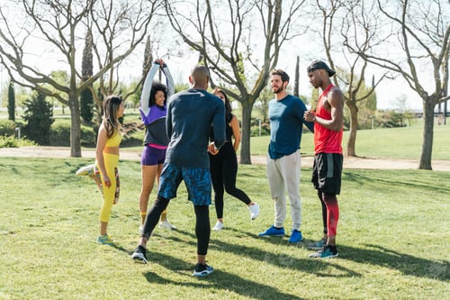 Preview: Group of friendly runners talking in a park before training. Selective focus.