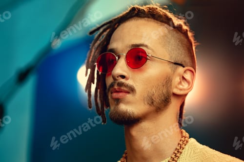 Preview: Portrait of a positive handsome caucasian guy with dreadlocks against blue background