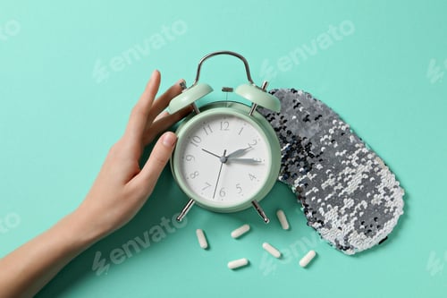 Preview: Sleep mask, alarm clock, pills and hand on green background, top view