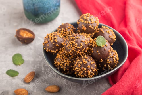 Preview: Chocolate caramel ball candies with almonds and a cup of coffee on a gray concrete background