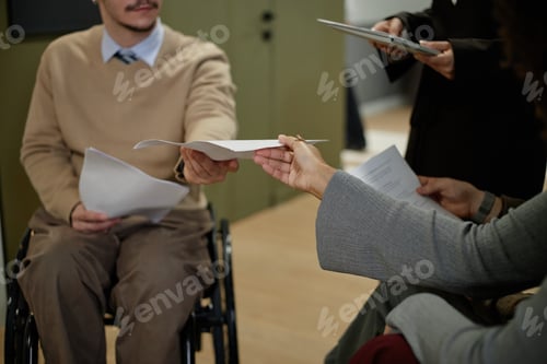 Preview: Caucasian Man with Disability Handing Document to Colleague