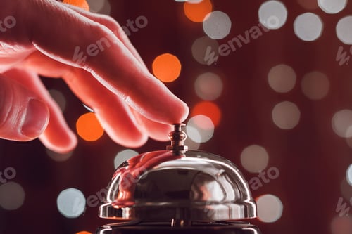 Preview: Hand pressing the hotel reception bell during Christmas holiday season