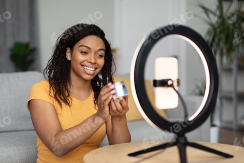 Preview: Attractive black woman blogger holding jar, making video ad for her blog, shooting video on