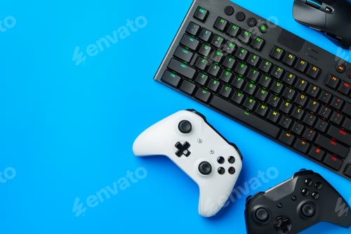 Preview: Computer keyboard and joystick on blue background top view