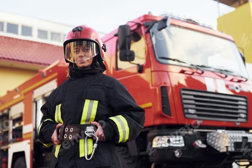 Preview: Female firefighter in protective uniform standing near truck