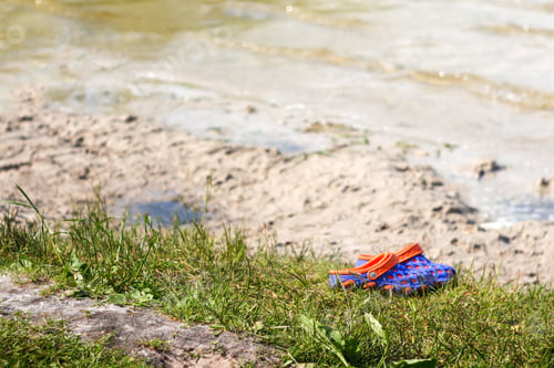 Preview: Purple and orange slippers at the beach on a beautiful sunny day. Slippers in the sand by the sea or