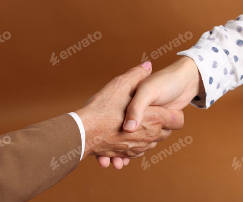 Preview: Women shaking hands on brown background, closeup