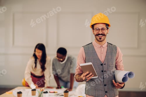 Preview: Male architect using blueprint and tablet in an office during a meeting