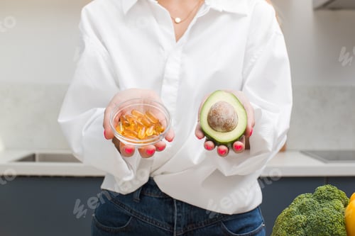Visualização: A mulher segura cápsulas amarelas e de abacate com vitamina D e ômega-3. Saúde e dieta.