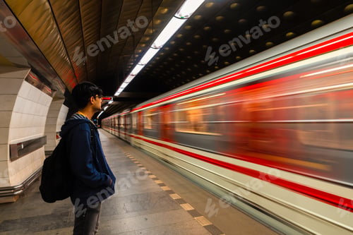 Preview: Fast moving train with motion blur and waiting traveler with a back pack at under ground station.