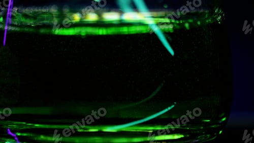 Preview: Close up of empty transparent glass being filled with green soda water. Stock clip. Wall with