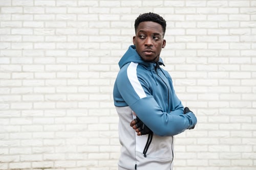 Vista previa: Young fit black man posing in front of a white brick wall.