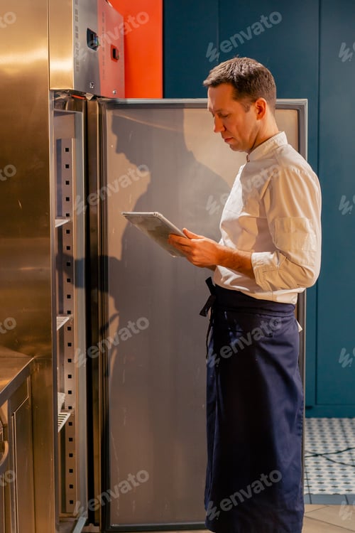 Preview: professional kitchen chef looks into the fridge and chooses ingredients for cooking food concept